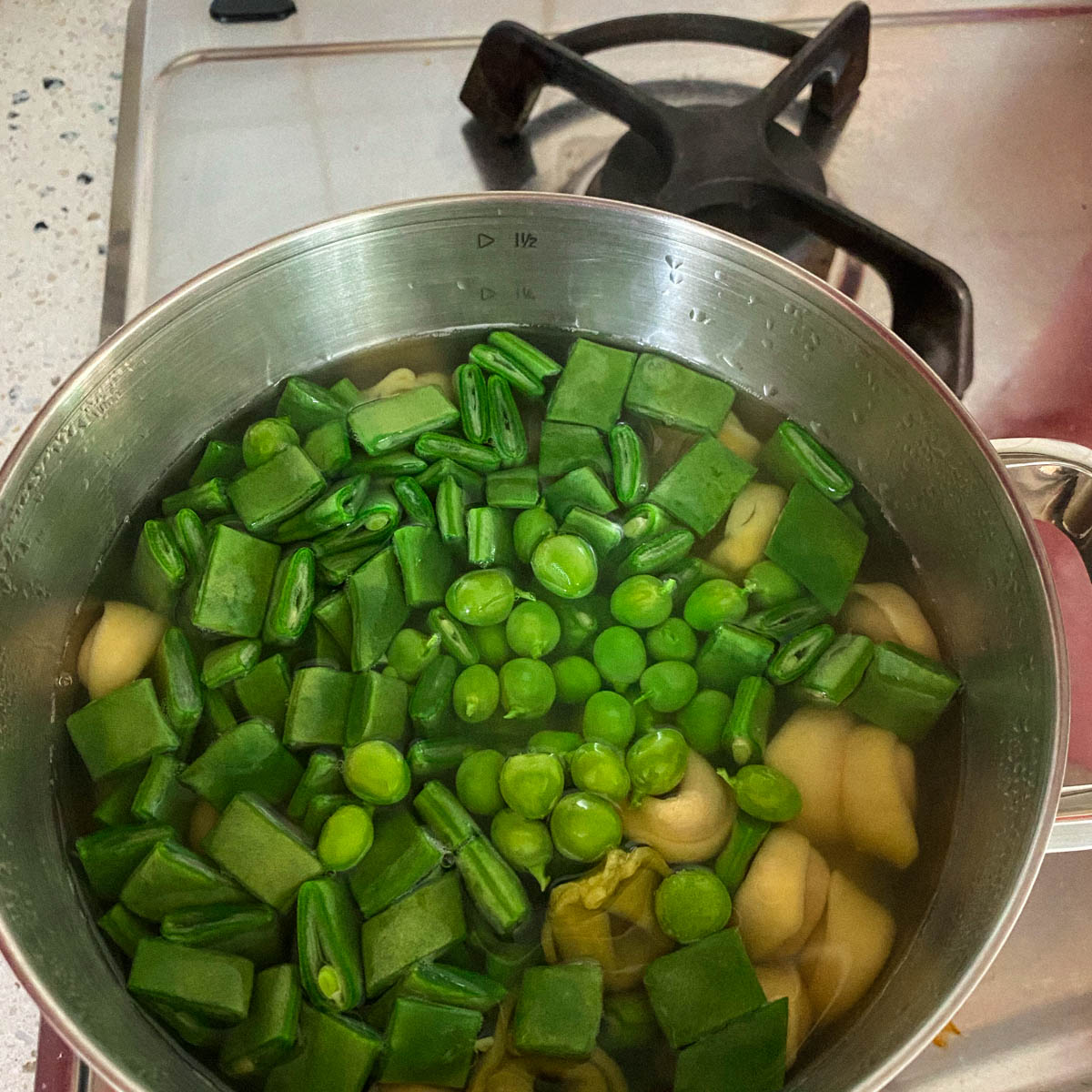 Kook de snijboon en erwten mee met de tortellini