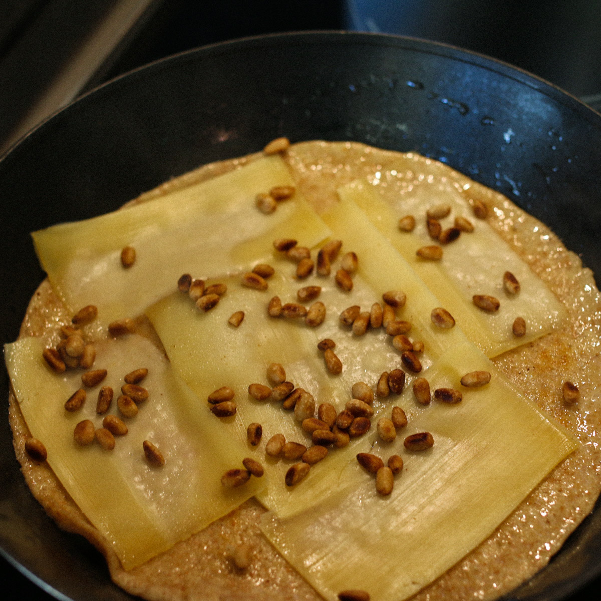 Plakjes kaas en pijnboompitjes op de pannenkoek