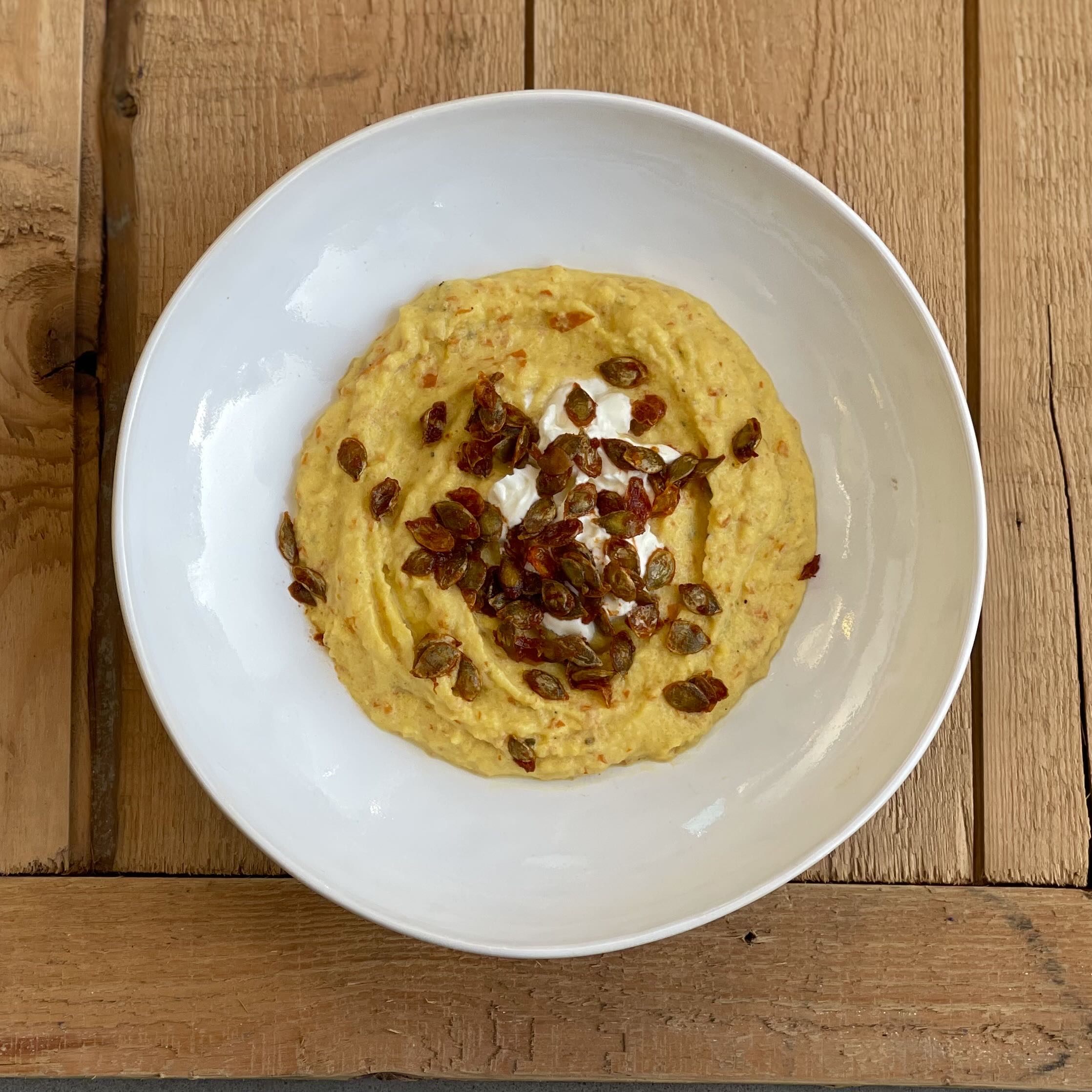 Serveer de pompoenpuree in een mooie ondiepe schaal en strooi er de pitten overheen.